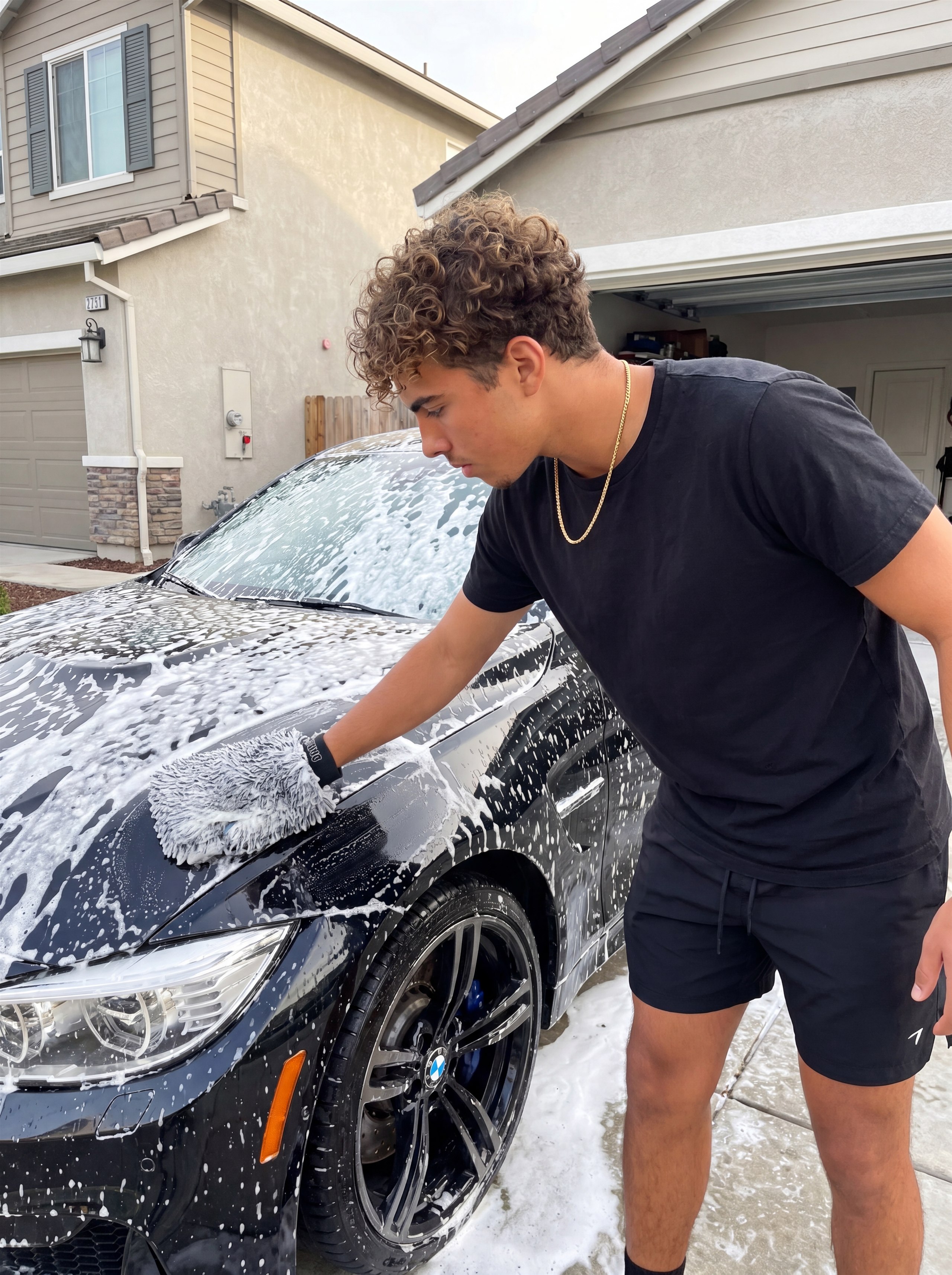 1 Day Detailz foam washing a black BMW in a customer driveway